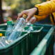 Person recycling a clear plastic bottle.